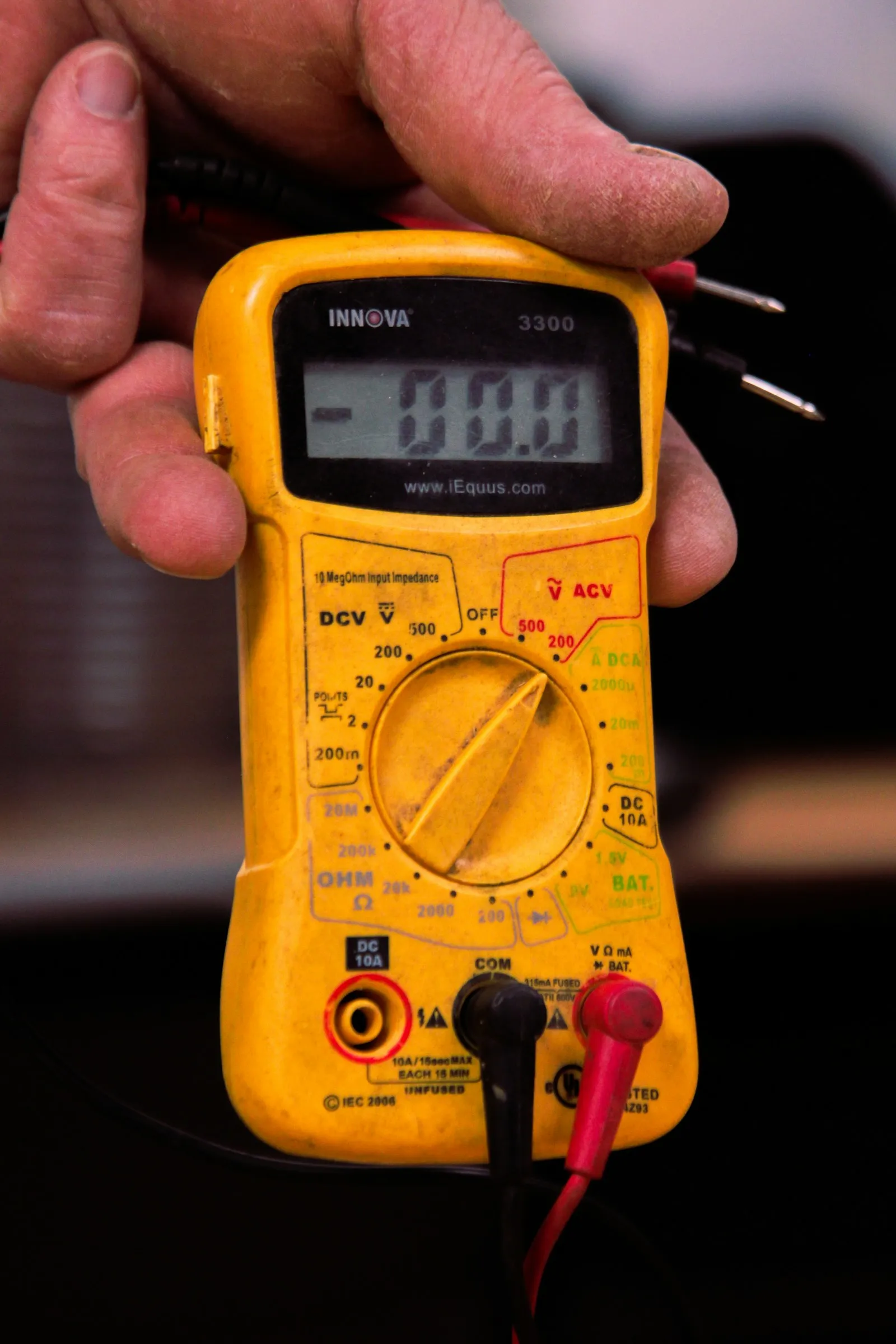 Hand holding a yellow digital multimeter
